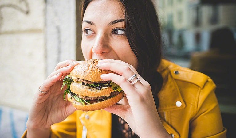 Young woman sitting eating an hamburger hand hold- hunger, food, meal ...